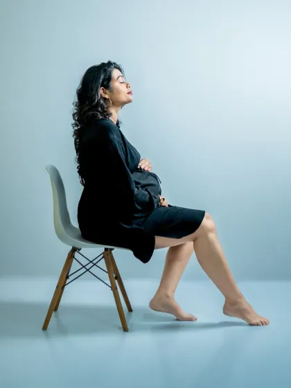 A minimalist portrait using colored studio lighting for a modern, artistic effect. The simple pose and clean background put all the focus on the mother's silhouette and peaceful expression.