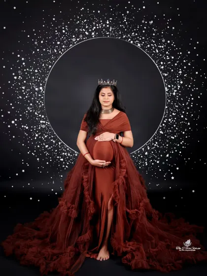 A celestial-themed solo portrait. The mom-to-be stands before a sparkling ring of light, creating a magical and stellar effect that celebrates the universe of new life.