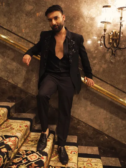 The same embroidered black suit, captured in a grand setting. The open-shirt styling gives it a modern, relaxed edge, proving that formal wear can be both elegant and contemporary.