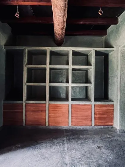 Built-in shelving made of polished cement and wood in the Hassan farmhouse. We design custom furniture and storage that is integrated into the architecture itself.
