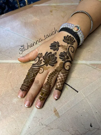 A bold and beautiful lotus vine design on the back of the hand. The dark, filled-in flowers make a striking statement.