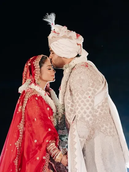 A quiet, intimate kiss amidst the grand celebration. This close-up shot captures the deep emotion and connection between the couple during their Varmala ceremony.