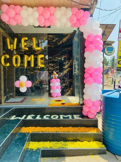 A shop-front style welcome decoration for a home, with a pink and white balloon arch and 'WELCOME' foil letters.