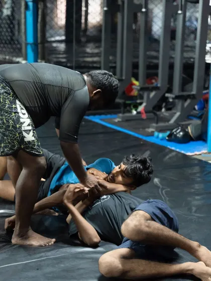 A coach instructing students during a grappling roll. This hands-on guidance is crucial for correcting mistakes and refining technique.