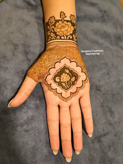 A close-up of the engagement mehndi, showing the central floral motif and the bold cuff design on the wrist.