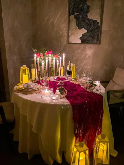 I can style a romantic dinner for two in the comfort of your home. This elegant table setting uses a rich red runner, tall candles, and floral accents to create a sophisticated and intimate dining experience.