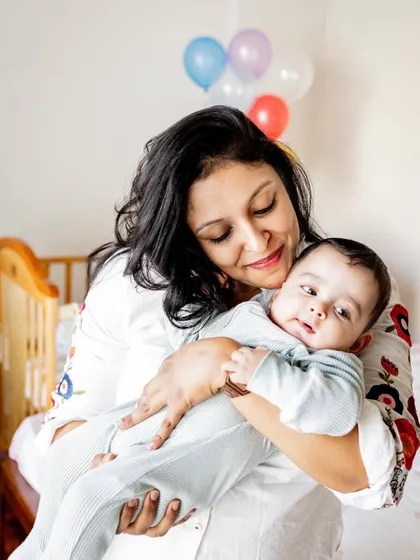 A mother holding her baby close in his nursery. This black and white version highlights the sweet expression and loving gaze between them.