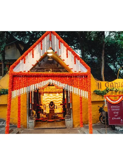 A grand entrance for a traditional ceremony at Ganjam Mantapa. The structure is covered in marigolds, creating a vibrant and auspicious welcome.