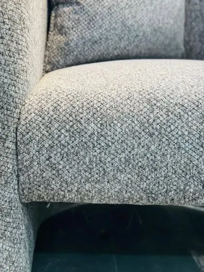 A macro shot of the textured grey fabric used on one of our custom armchairs. We offer a wide selection of premium, durable fabrics to ensure our furniture is both beautiful and long-lasting.