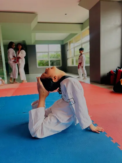 A student performs a deep backbend, showing the yoga-inspired flexibility training we incorporate into our classes.