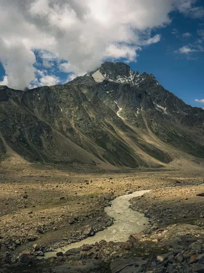 A majestic, snow-capped peak with a river flowing at its base in Spiti Valley. This is a classic landscape composition that showcases the raw beauty of the Himalayas.