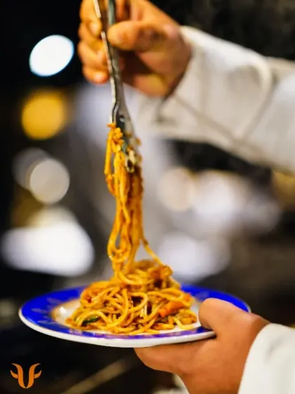 A chef serves a fresh helping of spaghetti onto a plate. My team is trained to serve with speed and professionalism, ensuring every guest gets a hot and delicious meal.