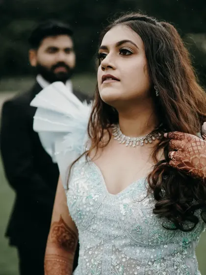 A portrait of the bride looking away thoughtfully, with the groom in the background. This composition creates a cinematic and story-driven feel for their engagement shoot.