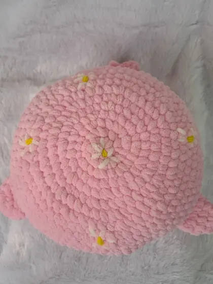 A top-down view of my pink whale pillow, showing the circular shape and the sweet, scattered daisy embroidery.