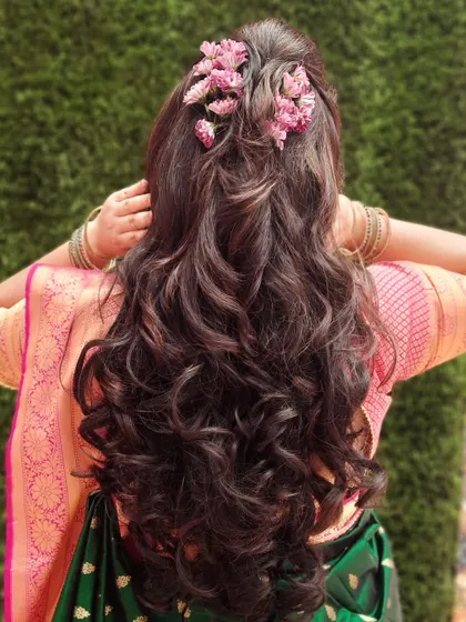 A romantic hairstyle with long, flowing curls decorated with small pink flowers. This look is perfect for a bride who wants a soft and dreamy appearance.