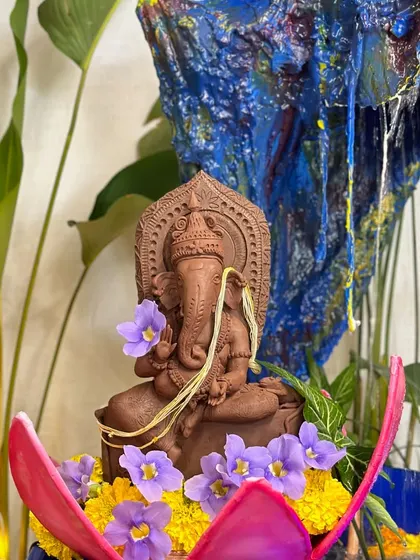 A finished clay Ganesha, adorned with fresh flowers before the pooja. Making your own idol adds a deep sense of connection to the celebration.
