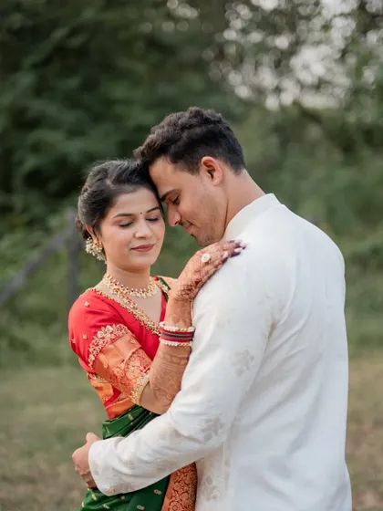 A tender and romantic portrait of the engaged couple embracing in a green field.