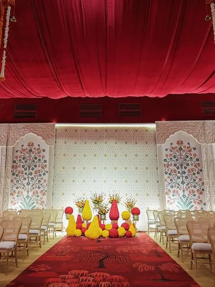 Another view of the traditional hall, showing the seating arranged on either side of the aisle, facing a stage with Pichwai-inspired backdrops.
