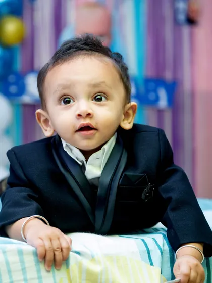 A close up shot capturing the wide eyed wonder of a one year old. His expressive face and dapper little suit make for an unforgettable first birthday portrait.