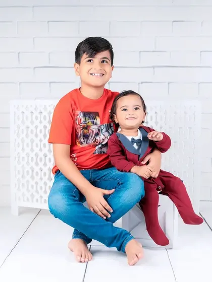 The special bond between brothers is on full display in this charming portrait. The older brother sits patiently while his baby brother sits happily on his lap.