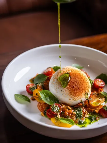 Another beautiful action shot of olive oil being drizzled over the Burrata Salad. This simple, high-quality ingredient is essential to authentic Italian cooking.