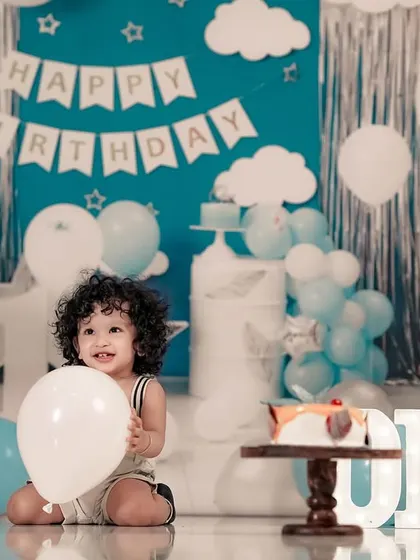 A happy little boy playing with a balloon during his first birthday cake smash photoshoot.