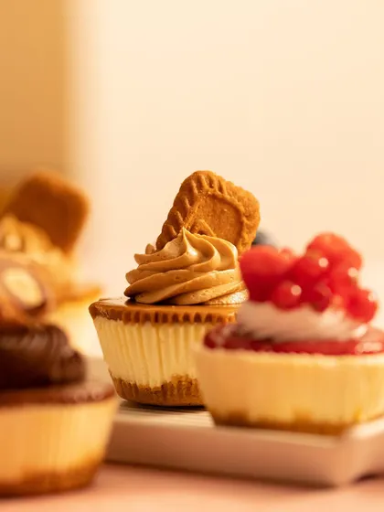 A close-up, artistic shot of my baby cheesecakes. The focus is on the Biscoff and Mixed Berry cheesecakes, highlighting their delicious toppings.