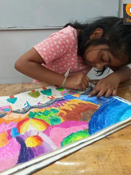 This student is working on a complex landscape, using oil pastels to blend colors. It's wonderful to see young artists tackle challenging compositions with such enthusiasm.