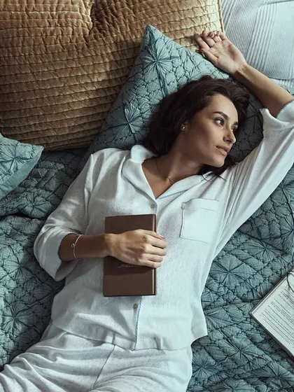 This top-down angle creates an intimate and personal view. The composition, with the open book and phone, tells a story of relaxation and modern life for this home decor brand.