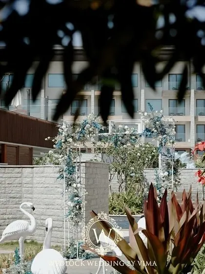 A chic tropical paradise for a brunch pool party. We used elegant white flamingo statues, a floral arch in shades of blue and white, and custom-designed linens to bring the theme to life.