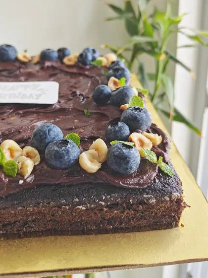 A close-up showing the texture of the sugar-free dark chocolate ganache, topped with crunchy hazelnuts and fresh blueberries.