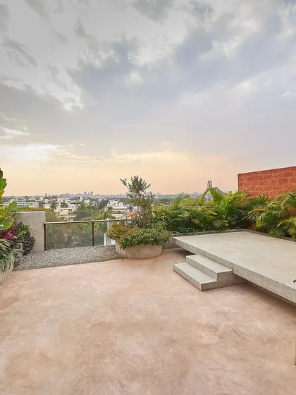 This rooftop terrace for the Magnolia Residence transforms an urban penthouse into a private oasis. We used a mix of lush tropical plants, pigmented cement flooring, and a raised platform to create a multi-level garden with views of the Bangalore city skyline.