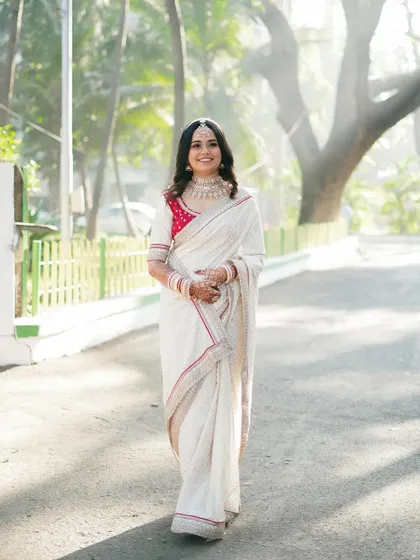 A classic portrait of the bride, smiling warmly. Her simple yet elegant white saree makes for a timeless and sophisticated bridal look.