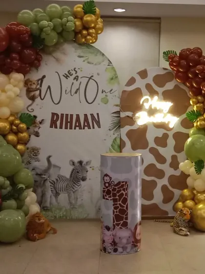 A "He's a Wild One" first birthday setup for Rihaan. This decoration features two themed backdrops, an organic balloon arch in earthy tones, a 'Oh Baby' neon sign, and a light-up number '1'.