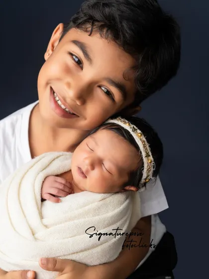 A close-up portrait of a big brother holding his newborn sibling, his smile radiating pride and love.