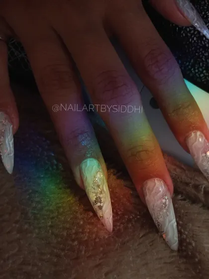 A beautiful shot of the stiletto nails under a rainbow light, highlighting the internal design.