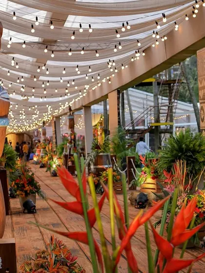 A view down the entrance walkway, showing the layers of detail, from the Tiki statues and tropical flowers to the string lights overhead.