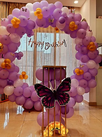 Here is another take on the butterfly theme, using a circular balloon ring in pastel purple and white. A large butterfly cutout on the central pedestal and a light-up rainbow add a touch of enchantment to this 4th birthday setup.