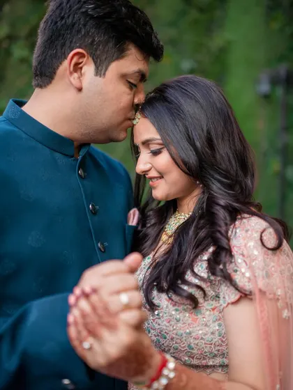 A sweet and romantic moment from an engagement shoot, with the groom gently kissing the bride's forehead.