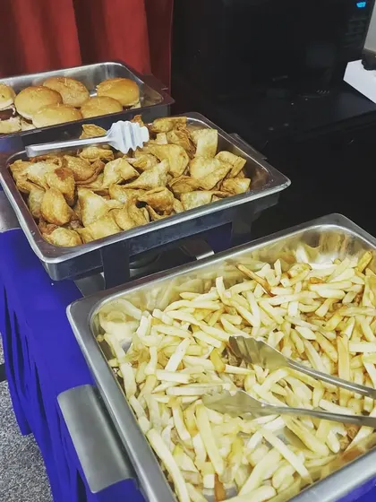 A close-up of some kid-approved party snacks. Trays of crispy french fries, cocktail samosas, and mini burgers ready to be devoured by hungry party guests.