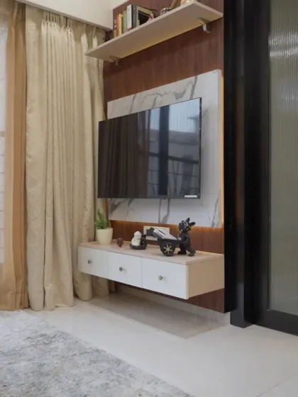 The floating TV unit in this living room is paired with a marble-finish back panel and wooden accents, creating a clean and contemporary entertainment zone.