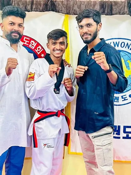 A student celebrates his new red belt with his coaches.