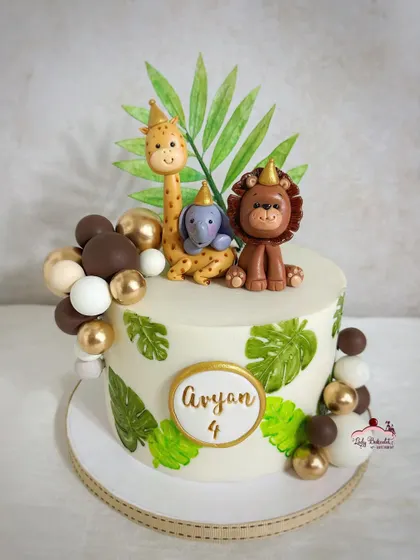 Rumble in the jungle! This cake features hand-painted monstera leaves, a gold and brown balloon garland, and cute, party-hat-wearing animal toppers.