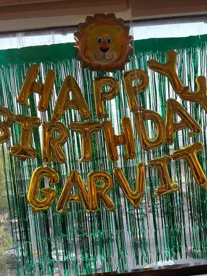 A simple but effective jungle-themed birthday banner. I used golden "Happy Birthday" foil balloons against a green fringe curtain, topped with a cute lion balloon to match the animal theme.