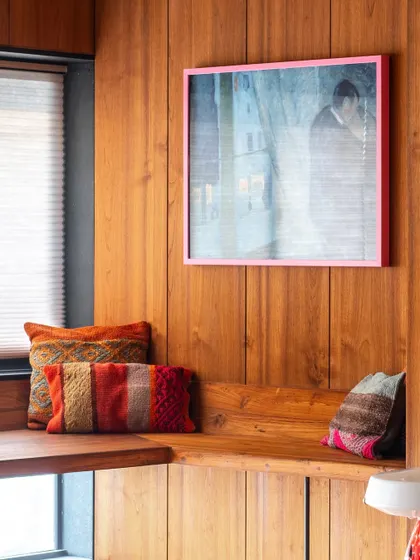 The warm tones of the teak wood are complemented by colorful textiles and art. This detail of the built-in seating shows how we balance natural materials with personal, vibrant accents.