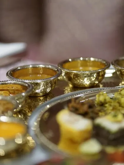 A close-up of a traditional Indian meal served in hammered golden bowls, showcasing the rich colors and textures of the different curries and dals.