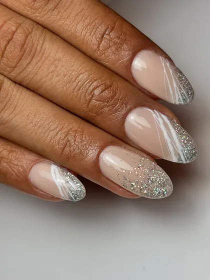 Go all glittery with this dazzling design. It features a cascade of silver glitter over a nude base, with abstract white spider gel lines for a modern, artistic touch.