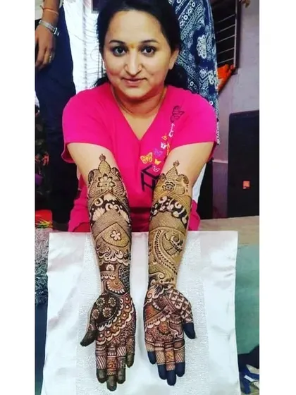 A happy client displaying her full bridal mehendi. The design is a lovely mix of traditional motifs and flowing patterns.
