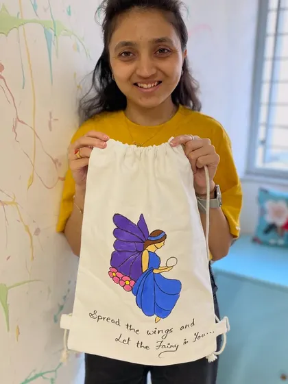 A participant shows off the fairy-themed backpack she painted. This workshop is perfect for unleashing your creativity on a functional item.
