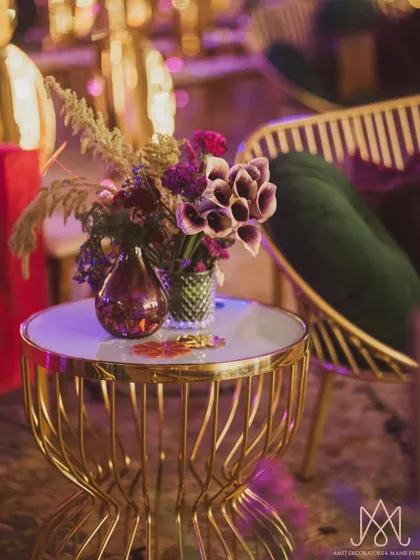 A beautiful floral arrangement on a gold side table, featuring dark, moody calla lilies and other exotic flowers.